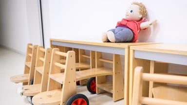 Holztische und eine Puppe in einer Kita
