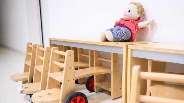 Holztische und eine Puppe in einer Kita