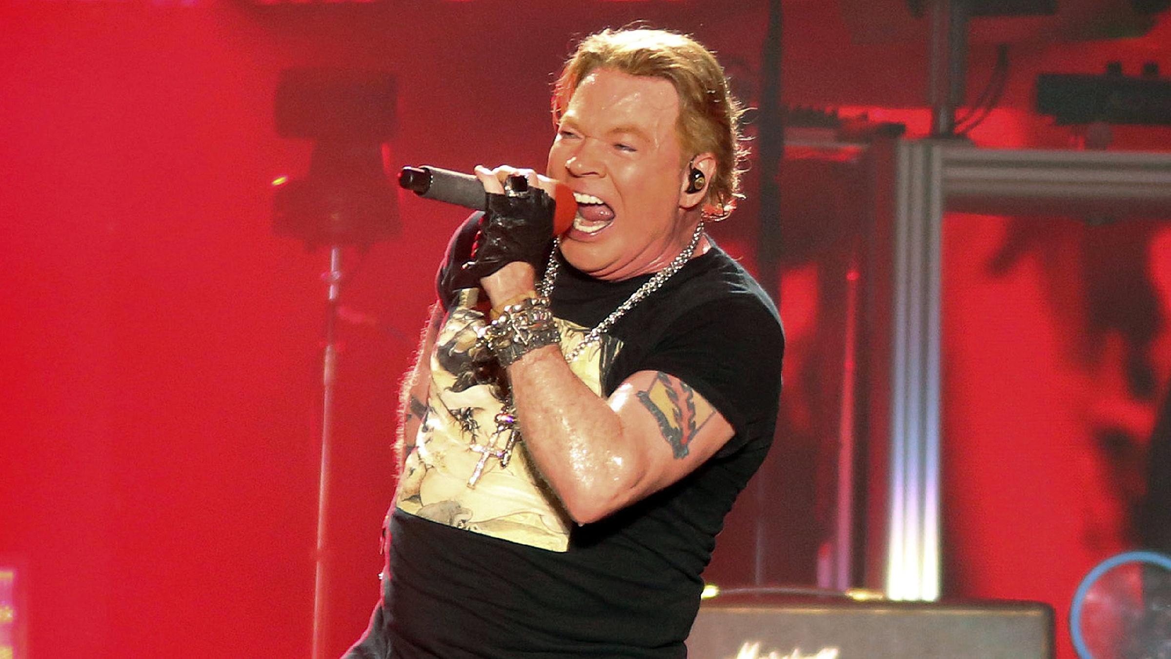 Frontman Axl Rose mit einem Mikrofon auf ener Bühne.