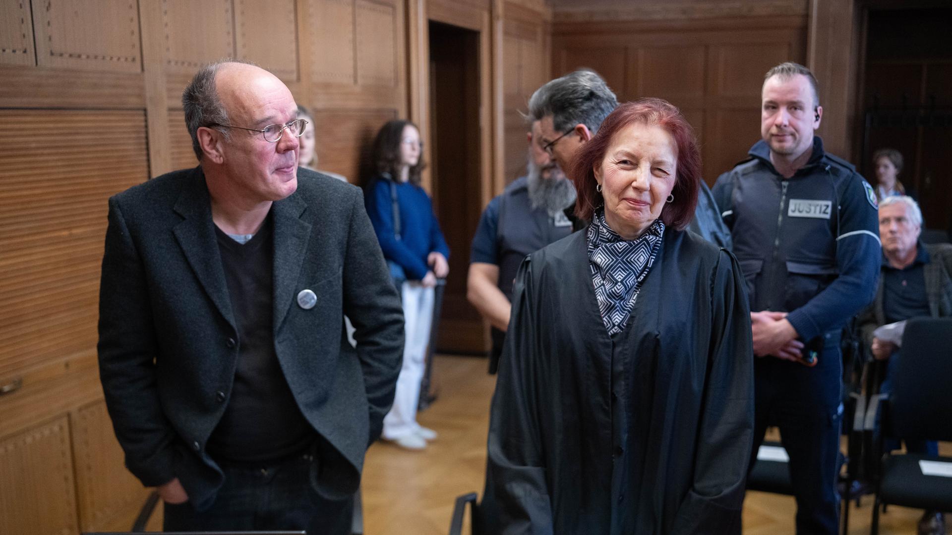 Der Kläger Marianus Krall (l) steht mit seiner Anwältin (vorne r) im Verhandlungssaal des Verwaltungsgerichts. 