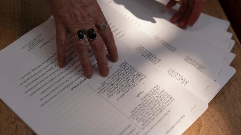 Eine Frau verteilt Kopien einer Klage gegen die Trump-Regierung für Medienvertreter vor einer Pressekonferenz im Büro des Justizministeriums von Oregon am Mittwoch, dem 23. April 2025, in Portland, Oregon. 