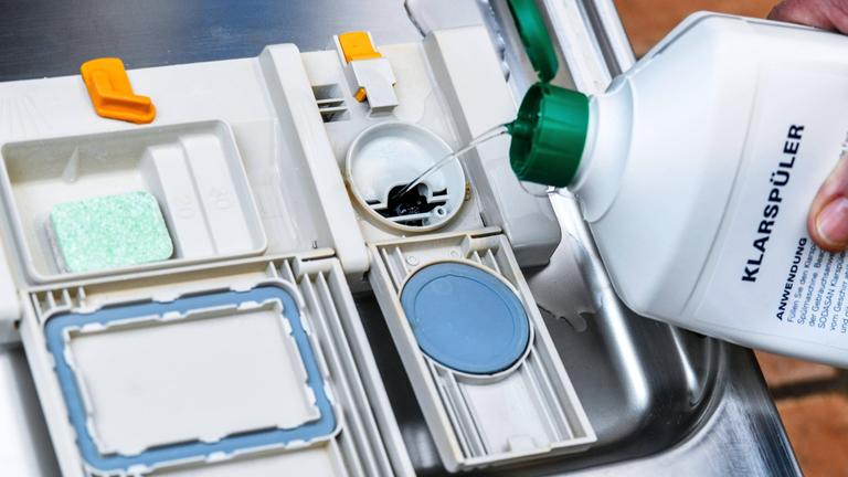 Klarspüler wird in das zugehörige Fach der Spülmaschine gekippt. 