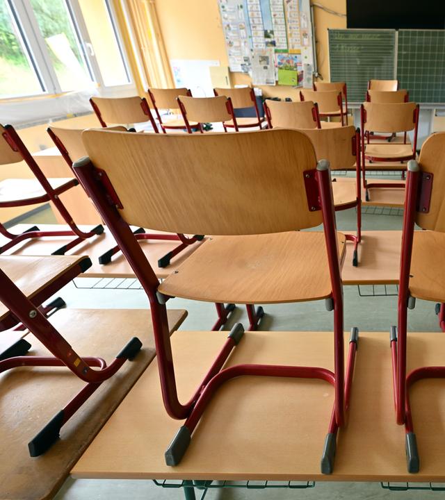 Die Stühle stehen auf den Tischen in einem leeren Klassenraum