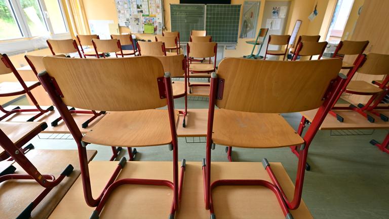 Die Stühle stehen auf den Tischen in einem leeren Klassenraum