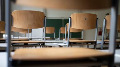 Stühle und eine Tafel sind in einem Schulraum zu sehen.