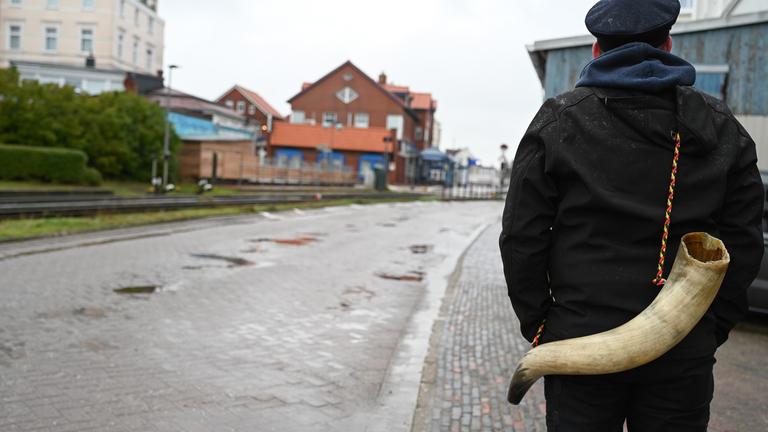Borkumer zieht mit einem Kuhhorn auf dem Rücken über die Insel