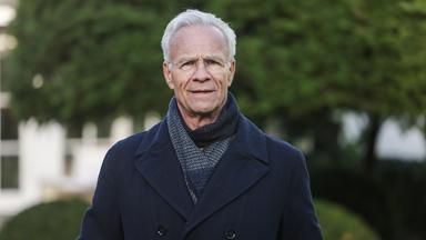 Der Schauspieler Klaus J. Behrendt (als Max Ballauf) steht am Drehort im Garten einer Villa.