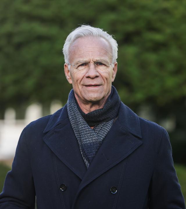 Der Schauspieler Klaus J. Behrendt (als Max Ballauf) steht am Drehort im Garten einer Villa.