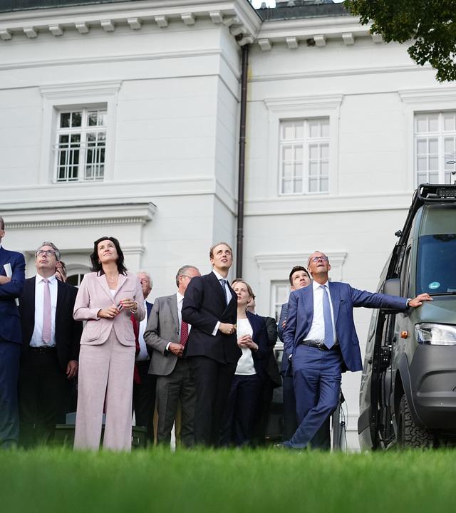 25.08.2026, Brandenburg, Neuhardenberg: Bundeskanzler Friedrich Merz (r, CDU) schaut sich bei der Klausurtagung der Bundesregierung im Schloss Neuhardenberg die Tytan-Drohne Hyperion zusammen mit seinen Kabinettskollegen an.