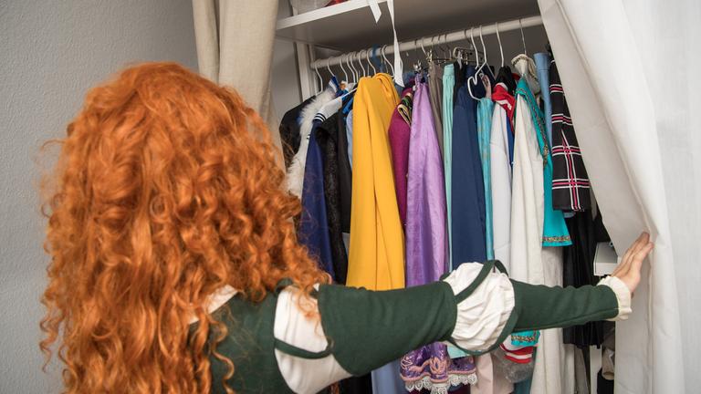 Eine junge Frau schaut in ihren Kleiderschrank.