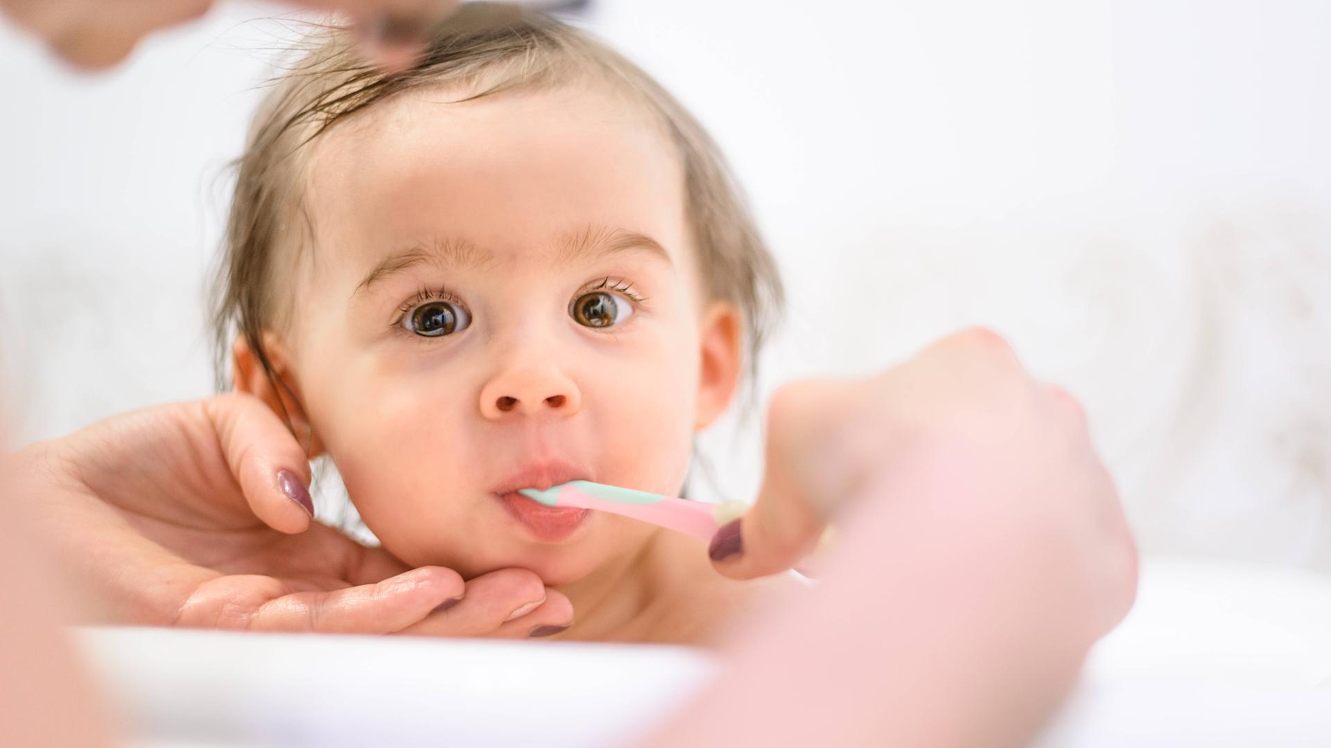 Ein kleines Kind bekommt die Milchzähne von seiner Mutter geputzt.