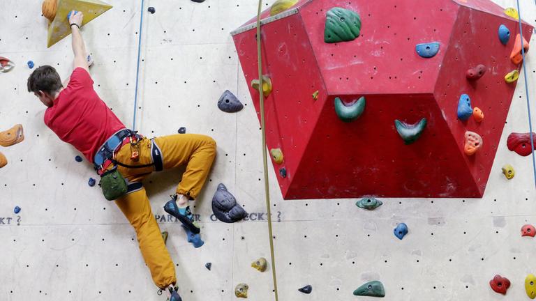 Bolderer an einer Kletterwand