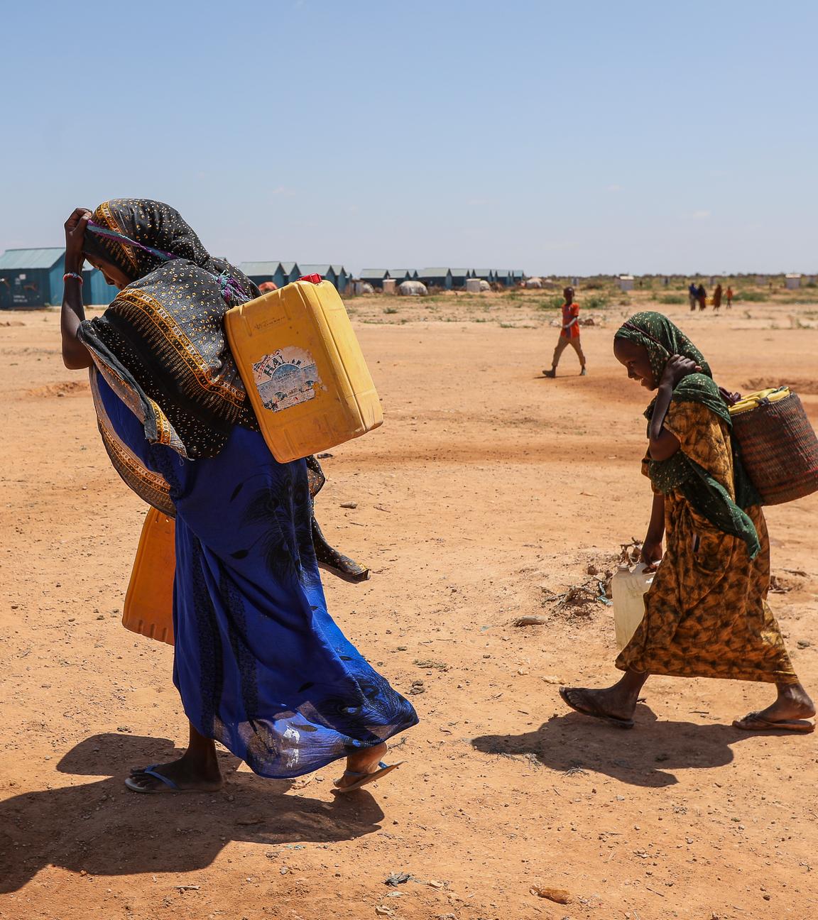 Eine Frau und Kinder transportieren Wasser nahe eines Flüchtlingscamps in Somalia.
