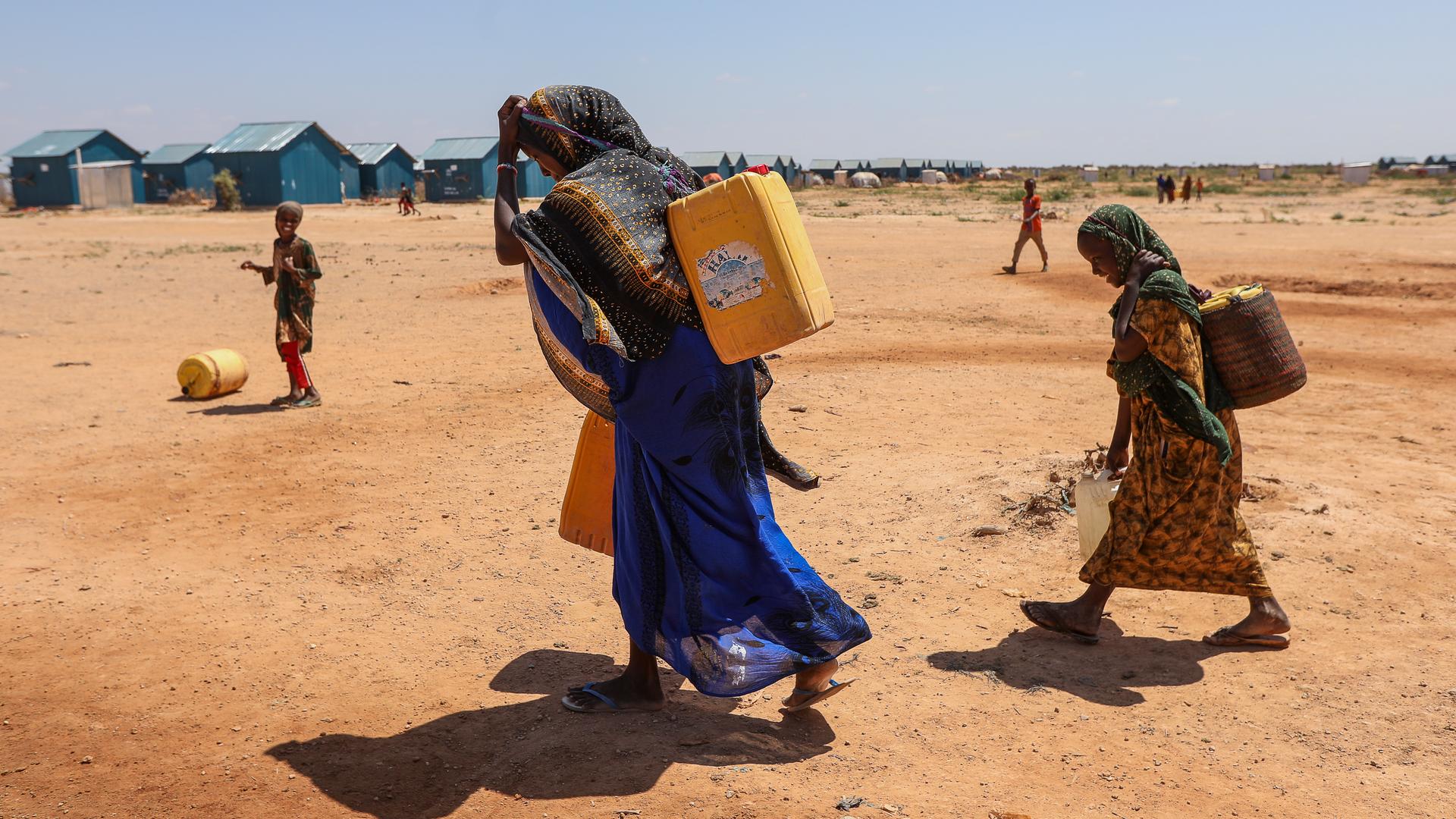 Eine Frau und Kinder transportieren Wasser nahe eines Flüchtlingscamps in Somalia.