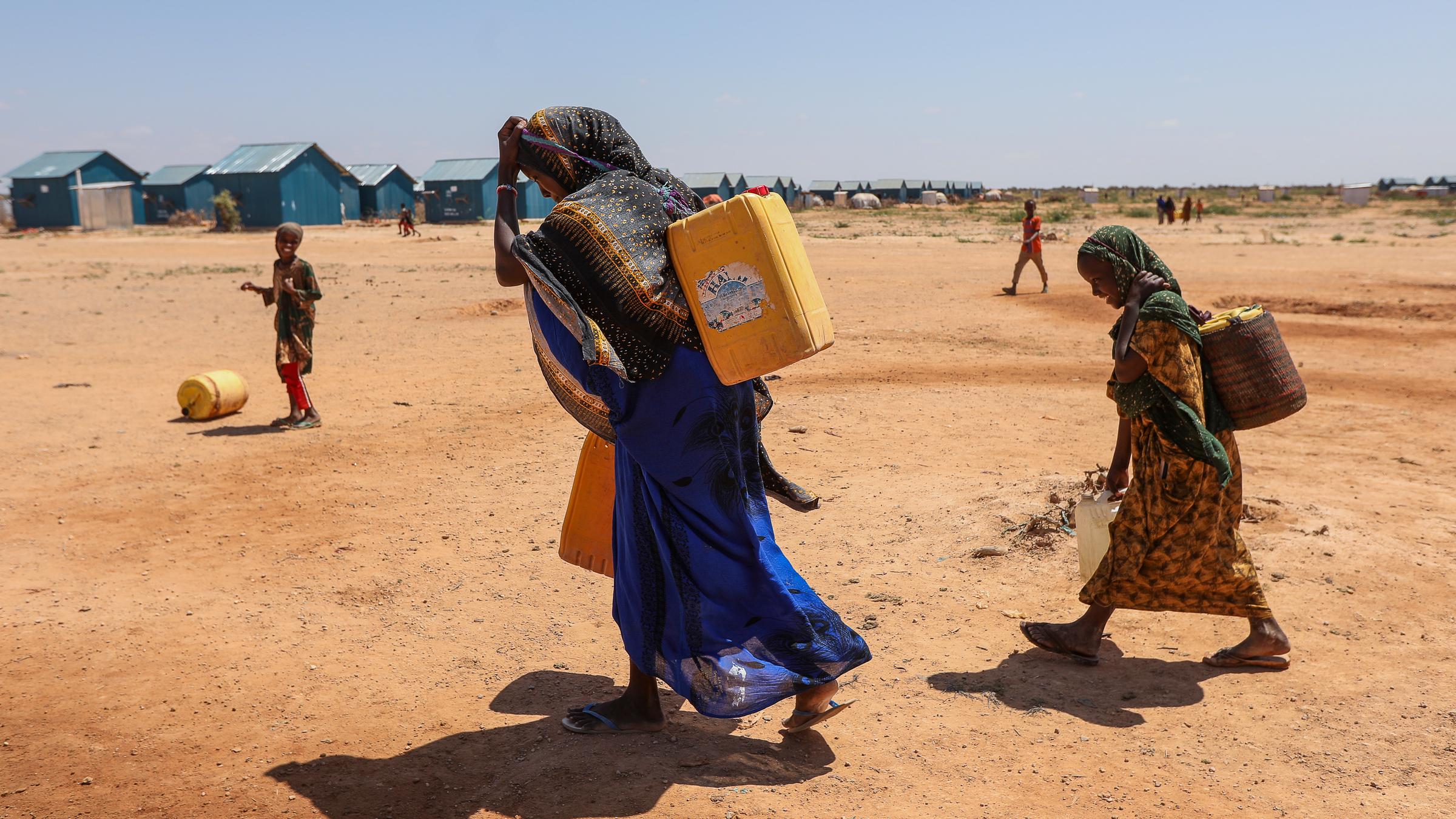 Eine Frau und Kinder transportieren Wasser nahe eines Flüchtlingscamps in Somalia.
