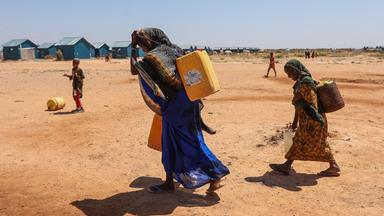 Eine Frau und Kinder transportieren Wasser nahe eines Flüchtlingscamps in Somalia.