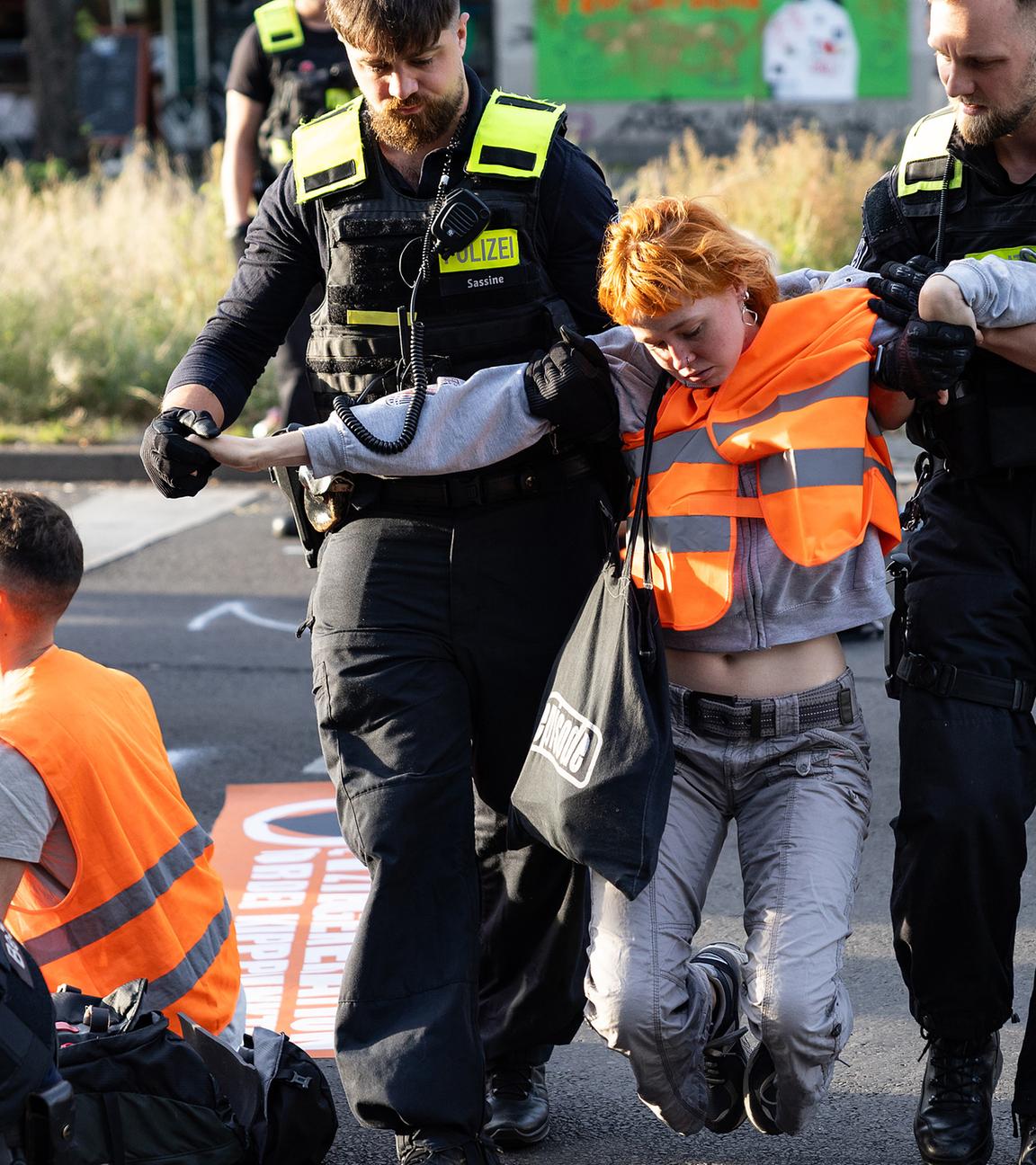 Eine Aktivistin wird von zwei Polizisten von der Straße getragen, aufgenommen am 18.09.2023
