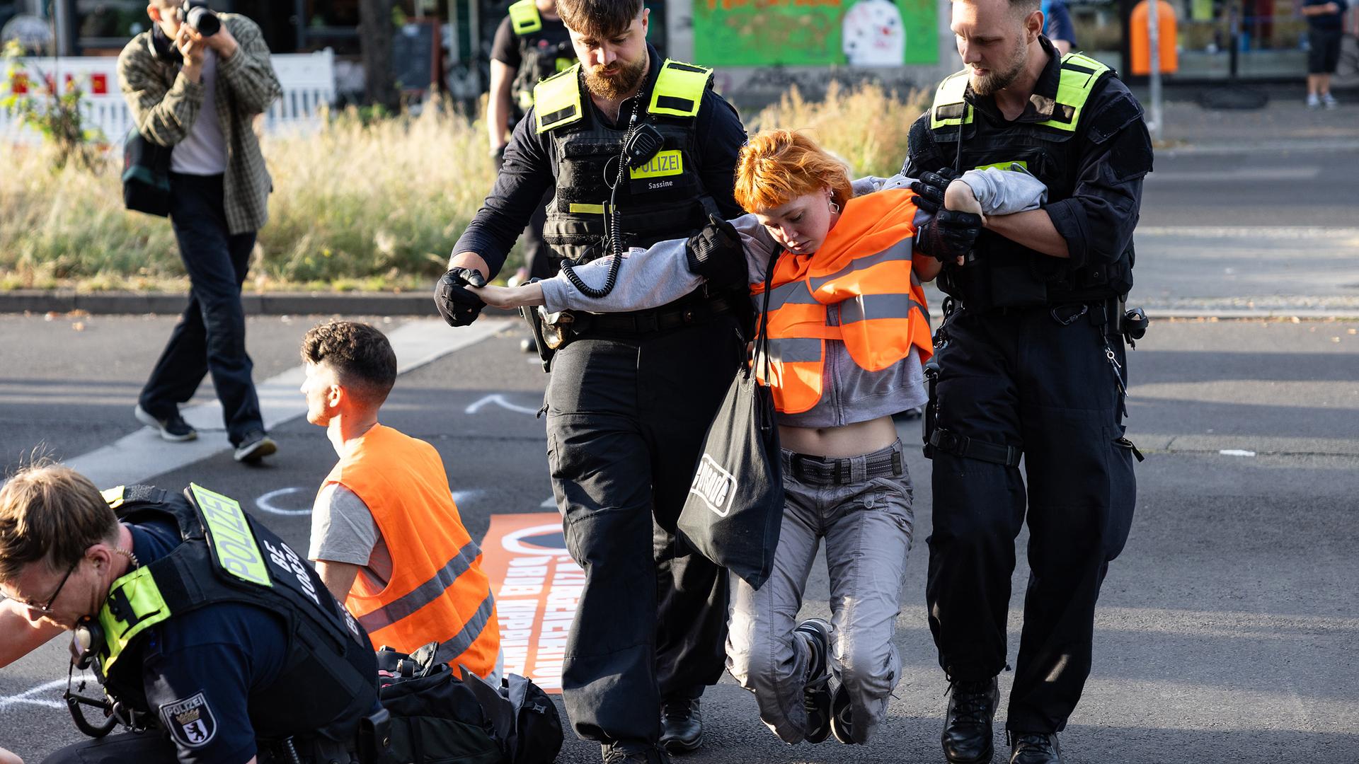 Eine Aktivistin wird von zwei Polizisten von der Straße getragen, aufgenommen am 18.09.2023