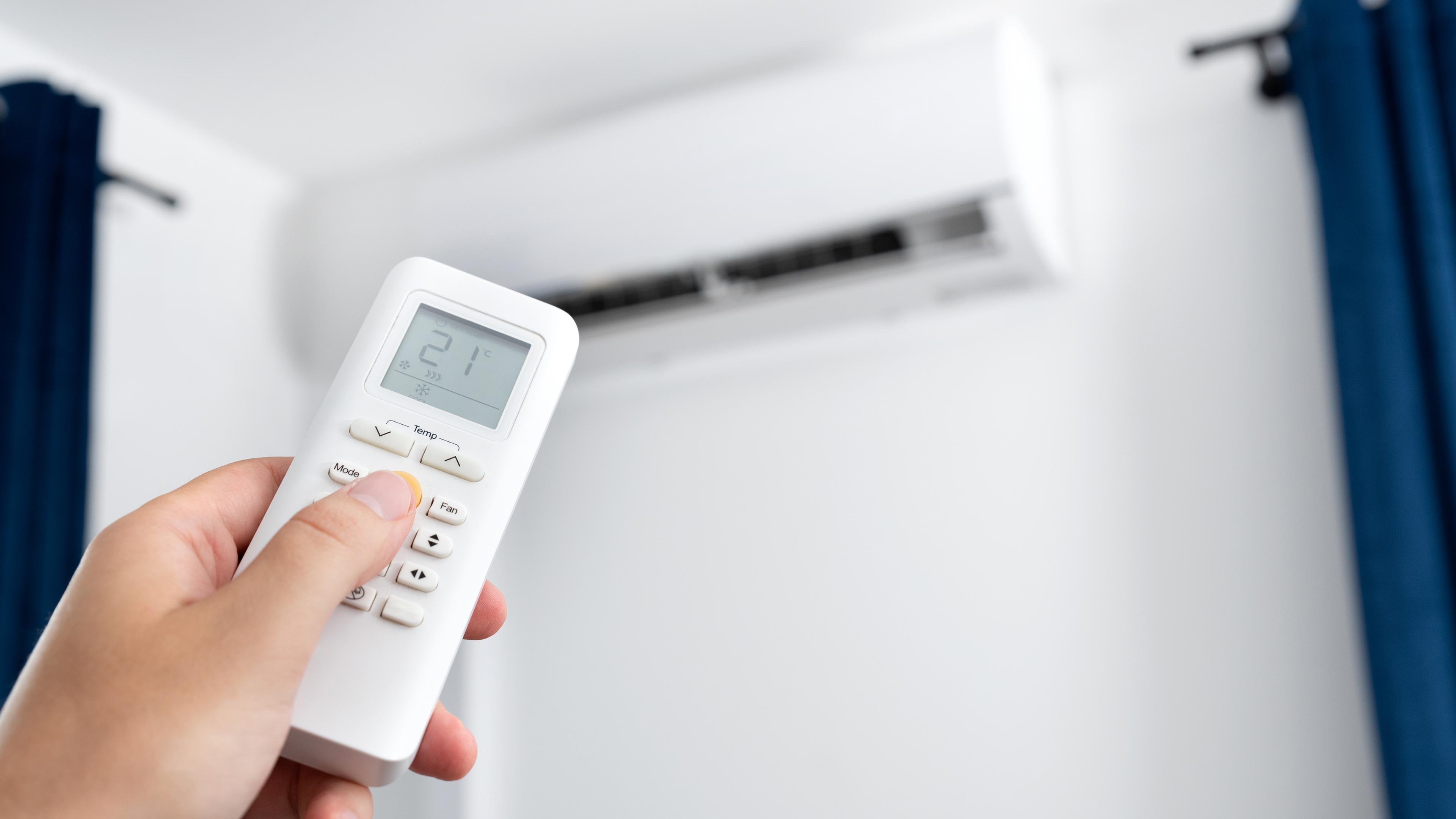 Hand hält die Fernbedienung für eine Klimaanlage