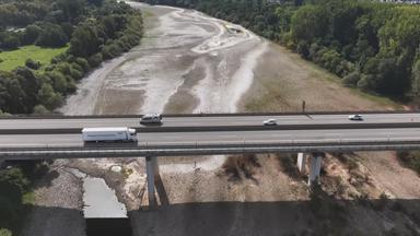 Ein leeres Flussbett unter einer Autobahnbrücke.