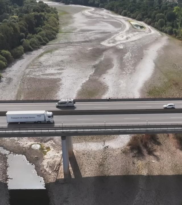 Ein leeres Flussbett unter einer Autobahnbrücke.