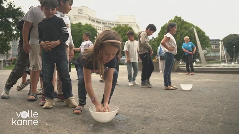 Spielende Kinder auf einem Hof, die mit kleinen Schüsseln mit Wasser spielen.