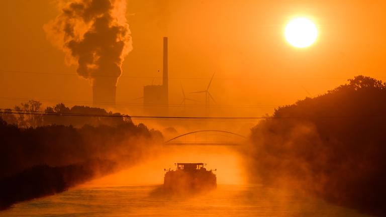 Symbolbild: Ein Schiff fährt auf dem Mittellandkanal durch den vom Sonnenaufgang in warmes Licht gefärbten Frühnebel in Richtung des Kraftwerks Mehrum im Landkreis Peine.  