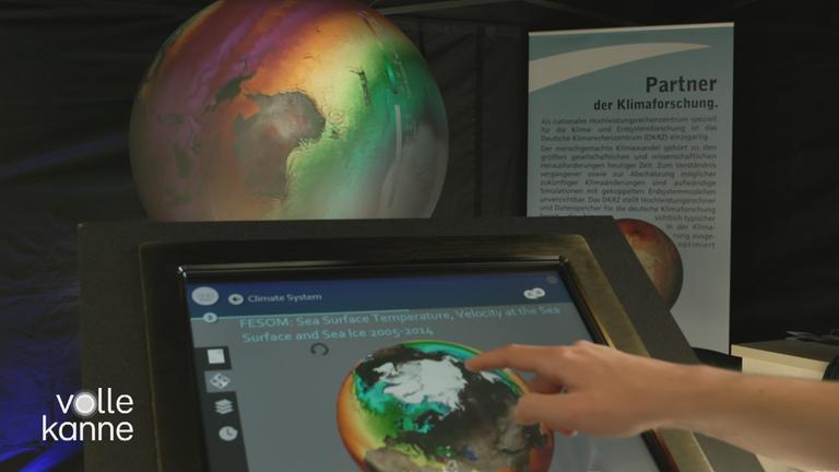 Hand zeigt auf Bildschirm mit Globus im Hintergrund