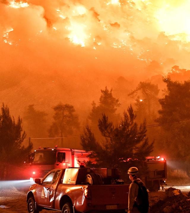 Zu sehen sind Feuerwehrmänner, die einen Waldbrand in Griechenland bekämpfen. 