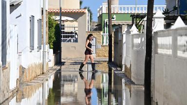 Eine Frau in Gummistiefeln überquert nach sintflutartigen Regenfällen eine Straße in Ostspanien.