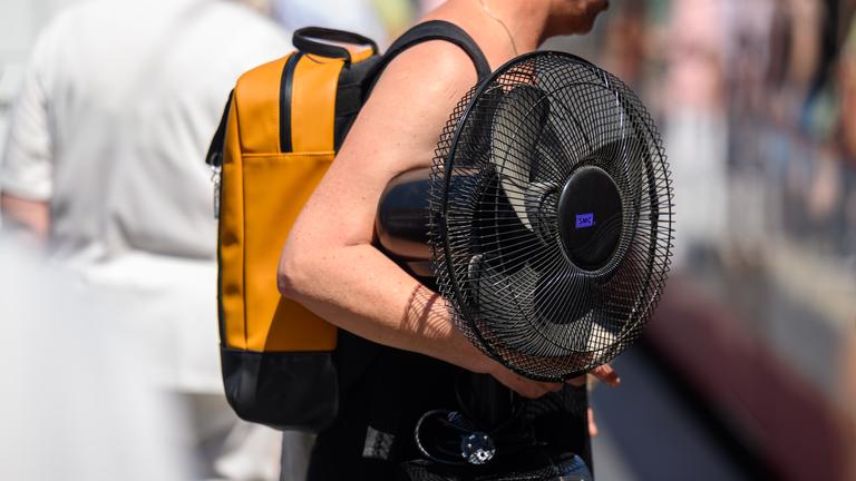 Eine Frau trägt einen Ventilator unter ihrem Arm.