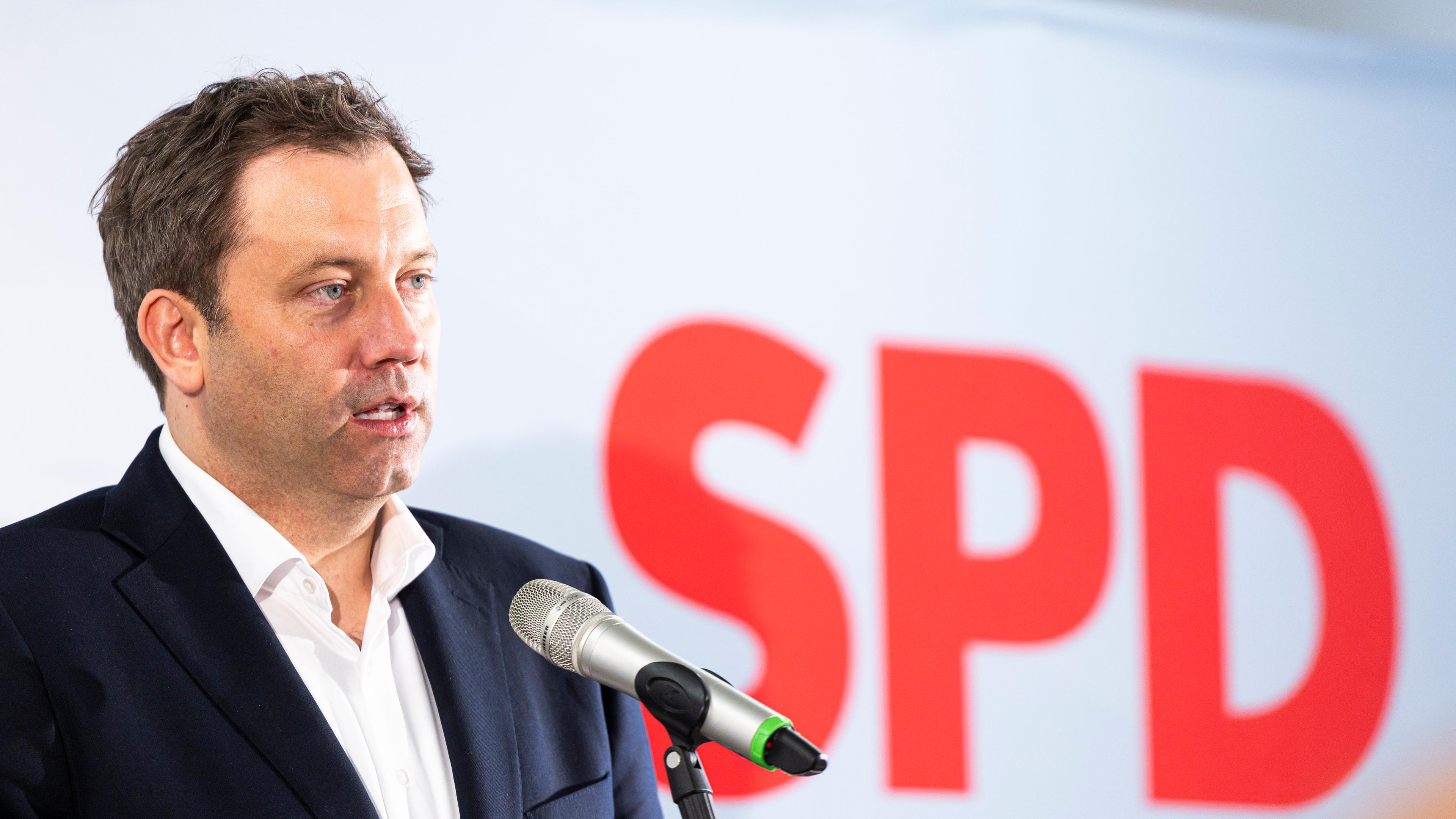 Klingbeil im Anzug mit SPD-Logo auf Leinwand im Hinergrund