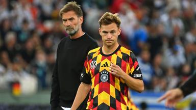 Nationalspieler Joshua Kimmich steht auf dem Fußballplatz, hinter ihm steht Bundestrainer Jürgen Klopp