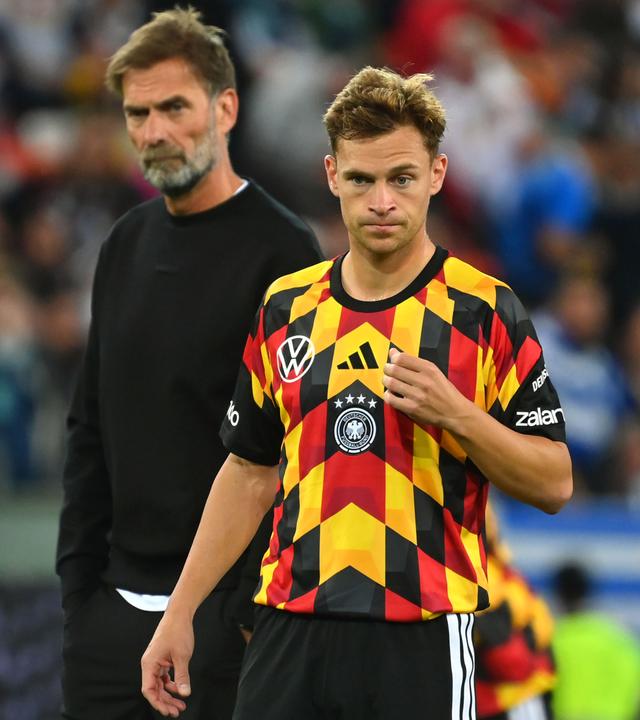 Nationalspieler Joshua Kimmich steht auf dem Fußballplatz, hinter ihm steht Bundestrainer Jürgen Klopp