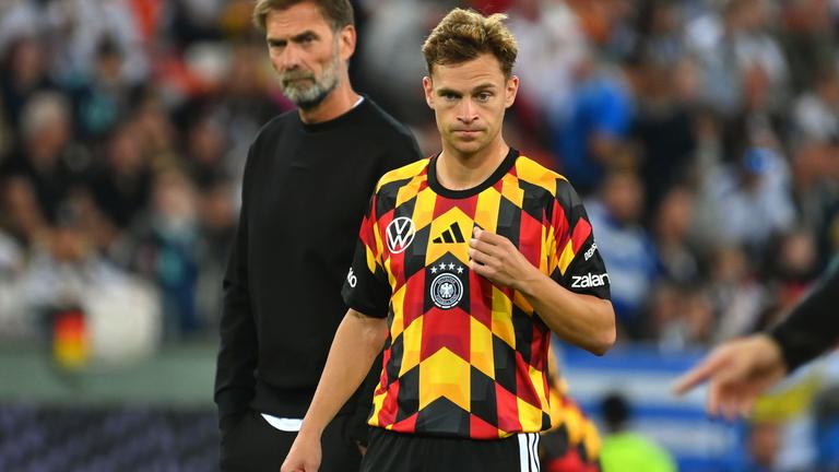 Nationalspieler Joshua Kimmich steht auf dem Fußballplatz, hinter ihm steht Bundestrainer Jürgen Klopp