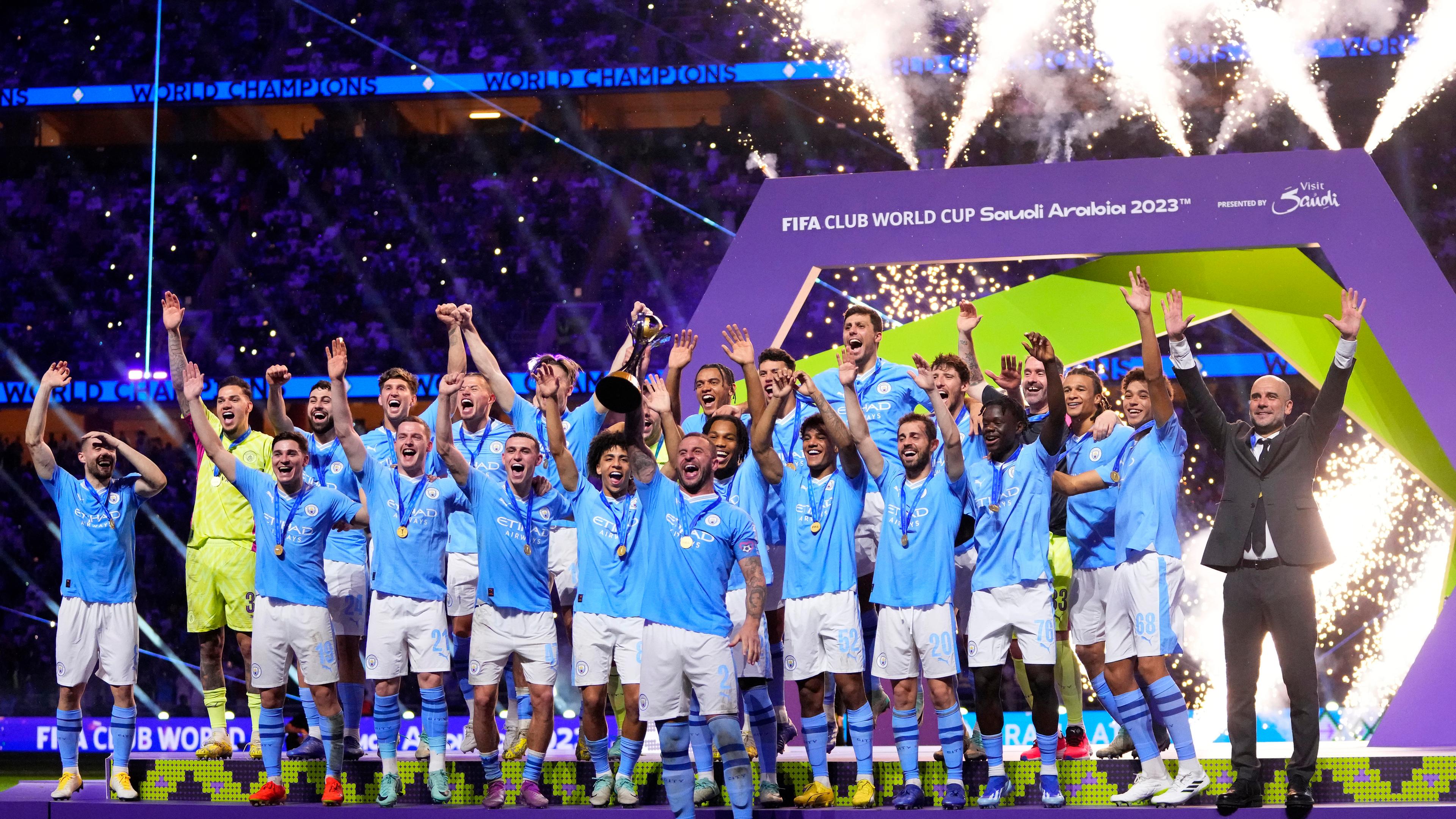 Das Team von Manchester City jubelt auf einer Bühne.