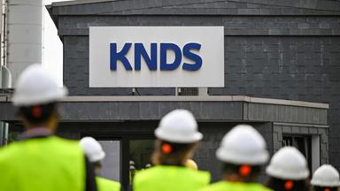 Besucher gehen während des Cleantech Future Festivals in Remscheid an einem Schild der KNDS Deutschland Tracks GmbH vorbei.