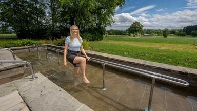 Eine Frau geht im Storchengang durch ein Wassertret-Kneippbecken.