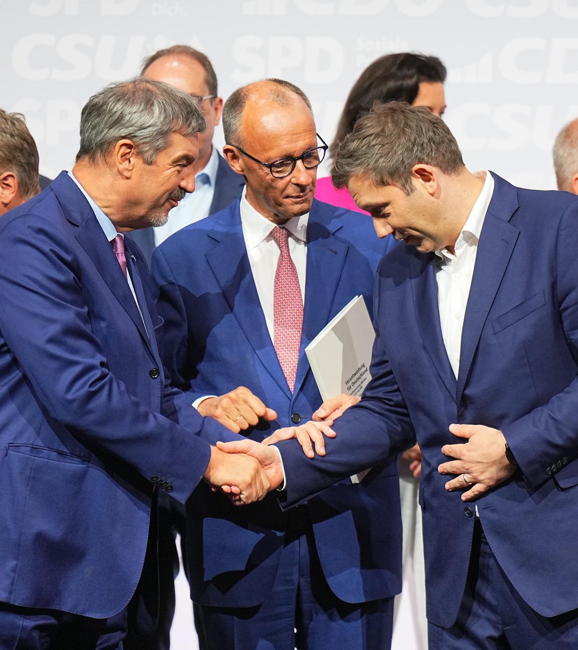CDU-Vorsitzender und -Kanzlerkandidat Friedrich Merz (M), CSU-Vorsitzender Markus Söder (l) und SPD-Vorsitzender Lars Klingbeil, designierter Bundesfinanzminister und Vizekanzler, geben sich nach der Unterzeichnung des Koalitionsvertrags von CDU, CSU und SPD zhur Bildung einer neuen Bundesregierung im Euref-Campus die Hand.
