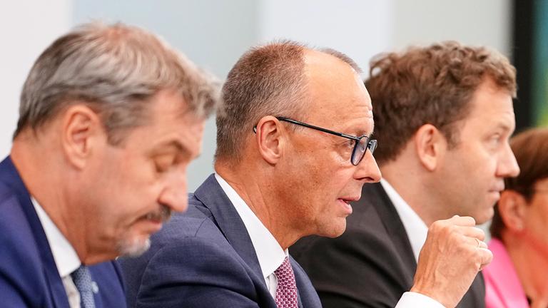 Bundeskanzler Friedrich Merz (CDU, 2.v.l) spricht neben Markus Söder (l-r), Ministerpräsident von Bayern und CSU-Vorsitzender, Lars Klingbeil, Bundesfinanzminister und SPD-Parteivorsitzender, und Saskia Esken, SPD-Parteivorsitzende.