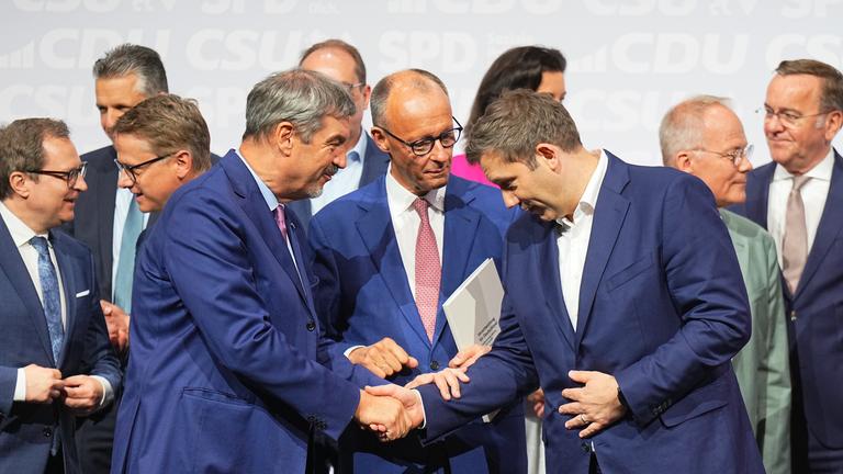 CDU-Vorsitzender und -Kanzlerkandidat Friedrich Merz (M), CSU-Vorsitzender Markus Söder (l) und SPD-Vorsitzender Lars Klingbeil, designierter Bundesfinanzminister und Vizekanzler, geben sich nach der Unterzeichnung des Koalitionsvertrags von CDU, CSU und SPD zur Bildung einer neuen Bundesregierung im Euref-Campus die Hand. 