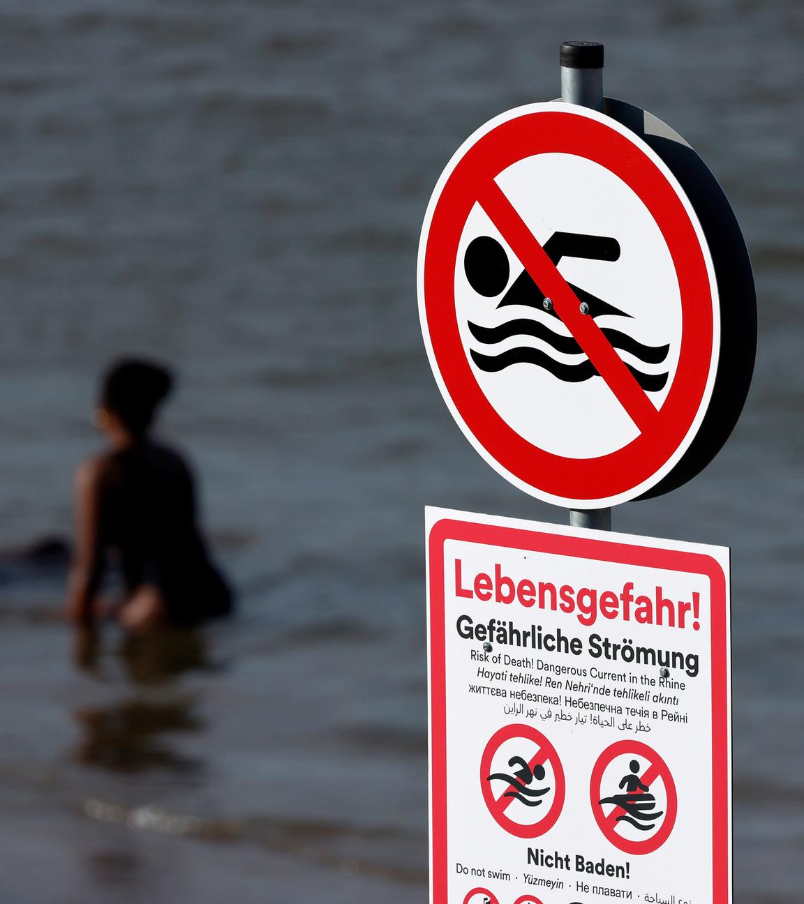 Ein Schild am Paradiesstrand in Düsseldorf warnt vor gefährlicher Strömung und Lebensgefahr beim Baden im Rhein.