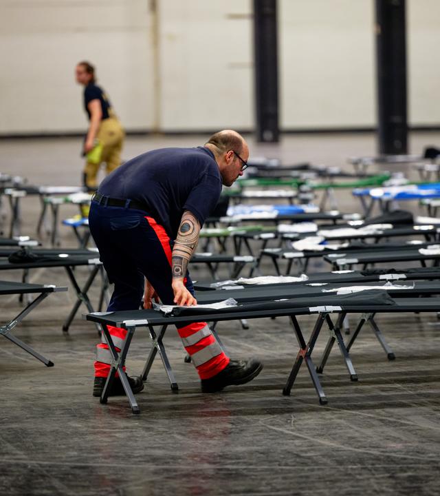 Ein Feuerwehrmann schiebt ein Feldbett in das Notfallversorgungszentrum