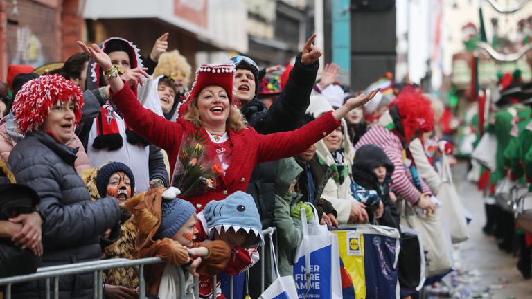 Karnevalisten feiern am Straßenrand beim Rosenmontagszug in Köln.