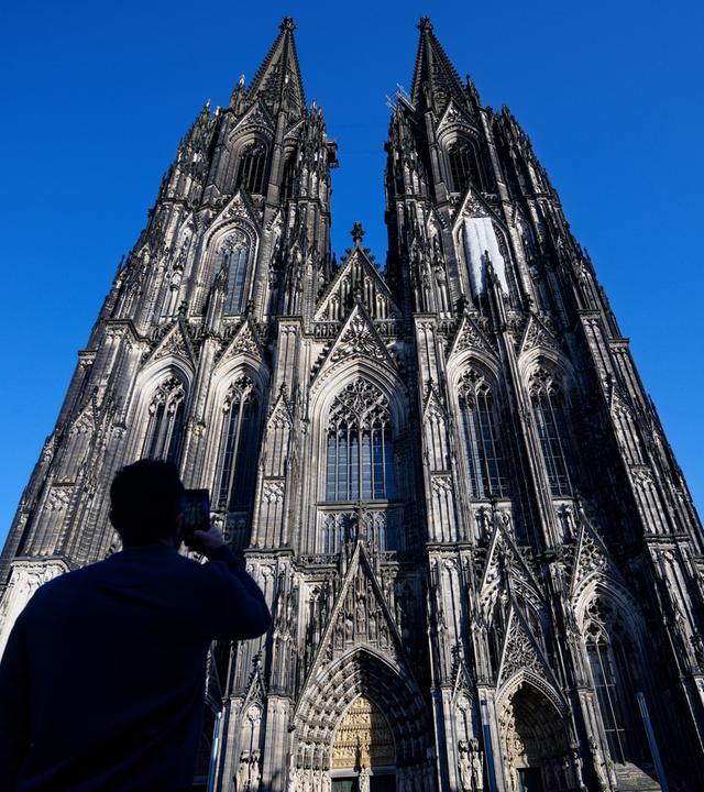 Touristen fotografieren den Kölner Dom, aufgenommen am 05.03.2026
