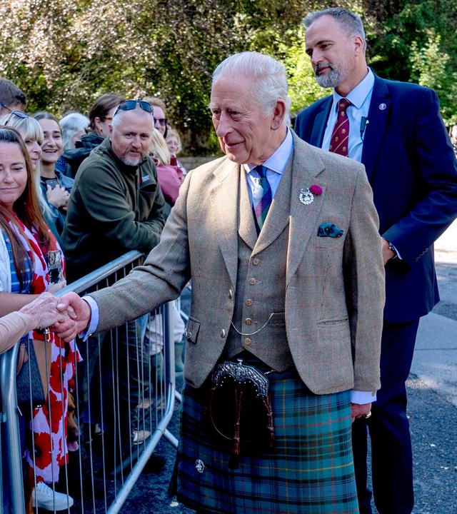 Auf dem Bild sieht man: Auf der rechten Seite König Charles, wie er Menschen gegenüber von ihm die Hand schüttelt. 