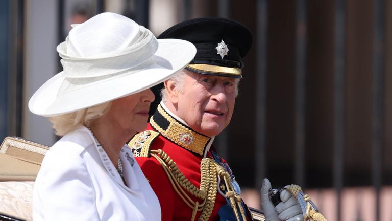 Königin Camilla und König Charles sitzen nebeneinader in einer offenen Kutsche