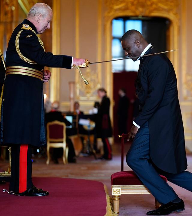 König Charles (rechts) schlägt den Schauspieler Idris Elba mit einem Schwert zum Ritter.