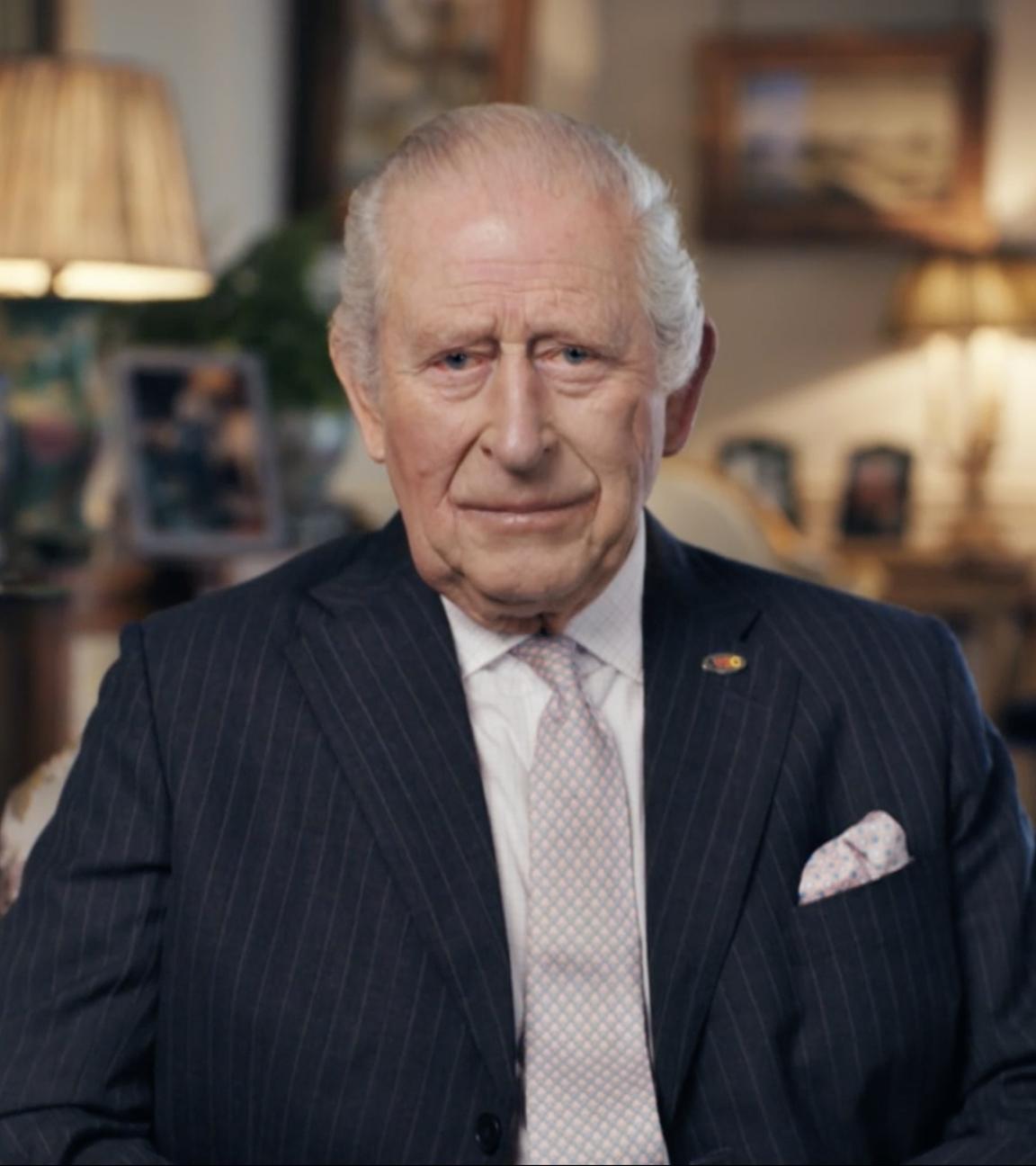 Der britische König Charles sitzt in Uniform auf einem Stuhl.