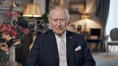 Der britische König Charles sitzt in Uniform auf einem Stuhl.